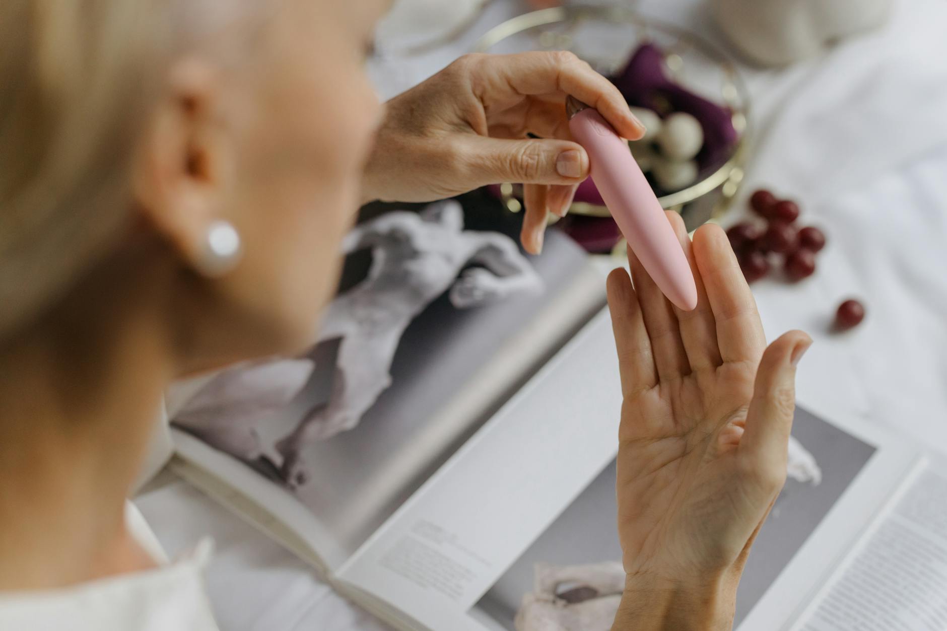 Woman holding blue and pink silicone vibrators in a contemplative manner