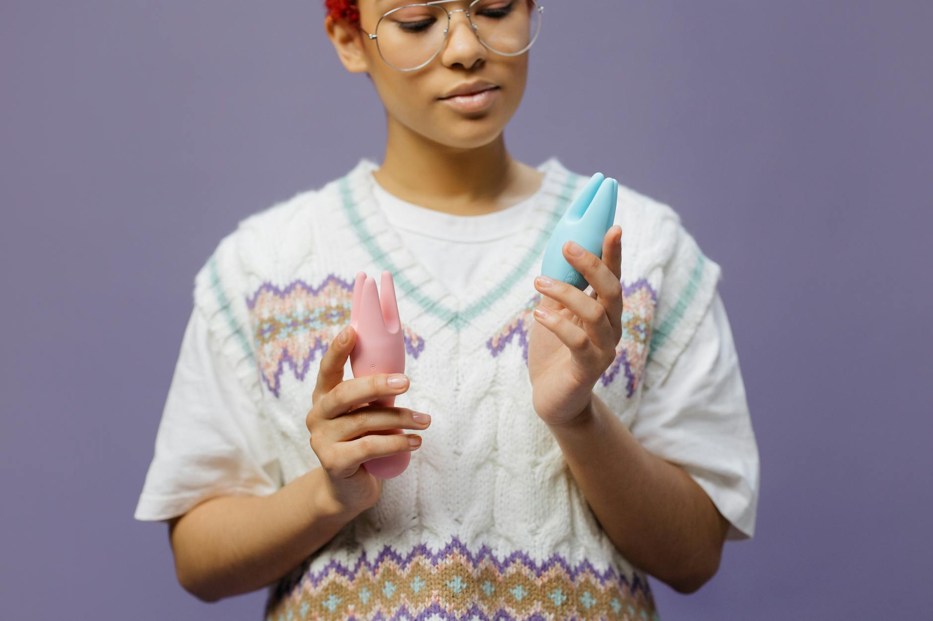 Woman holding a blue silicone vibrator with a thoughtful expression, exploring ways to manage clitoral sensitivity