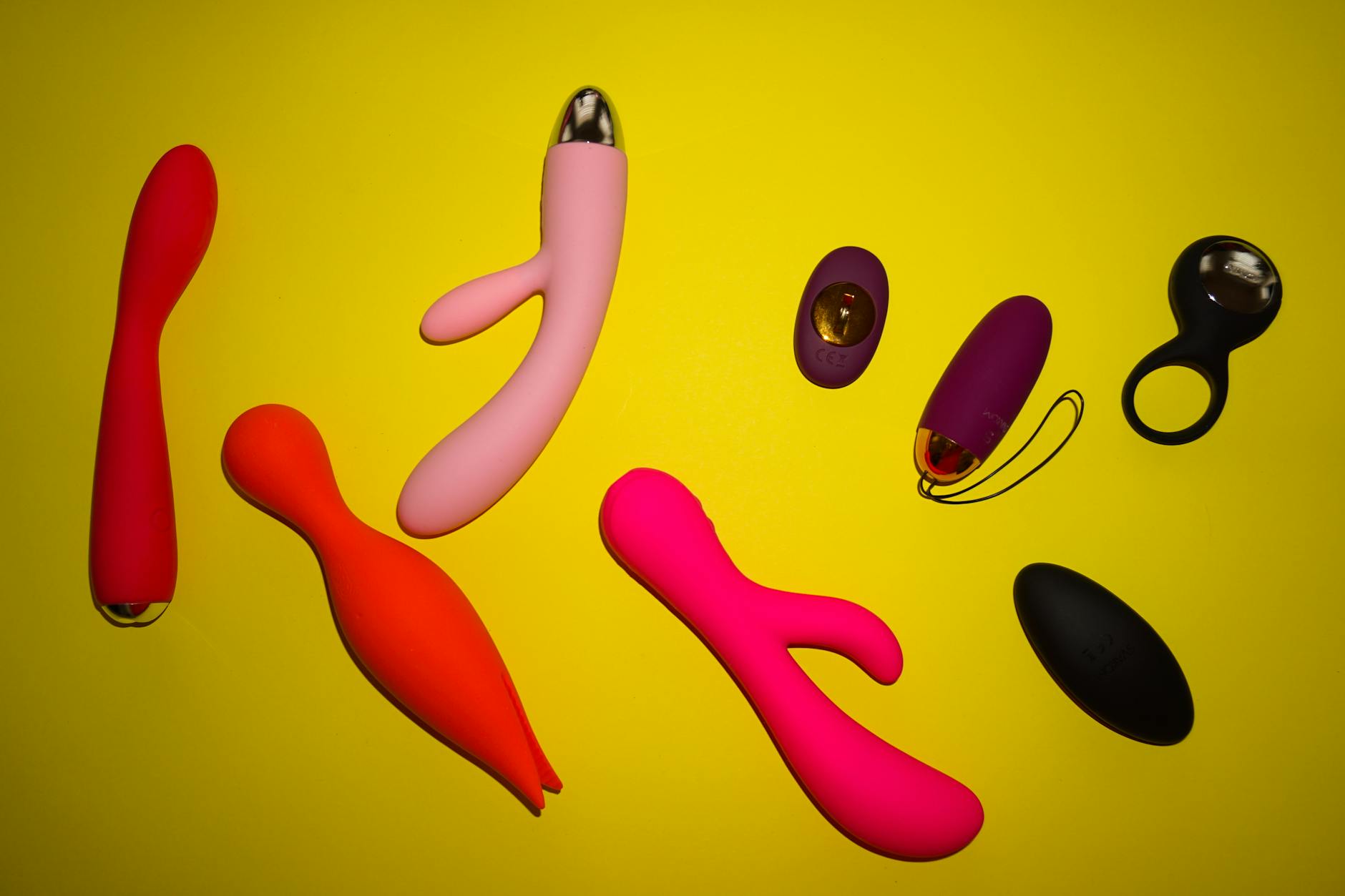 A woman holding colorful silicone vibrators and considering her options for pleasure recovery