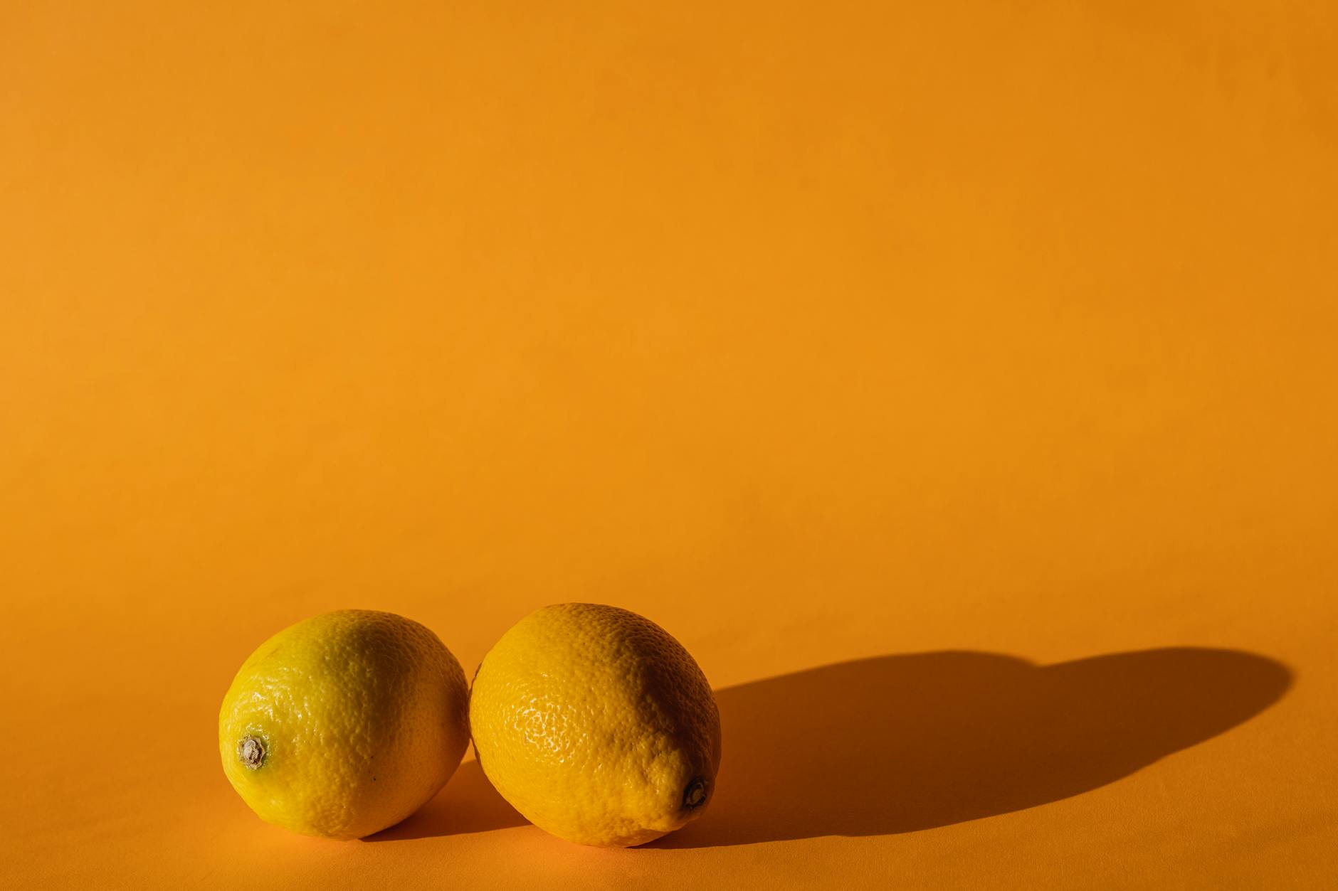 Blue vibrator surrounded by flowers and citrus slices on a bright yellow background
